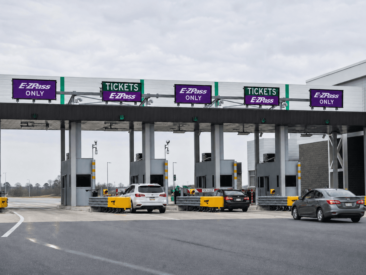 A car driving through an open-road electronic highway toll gantry on a clear day