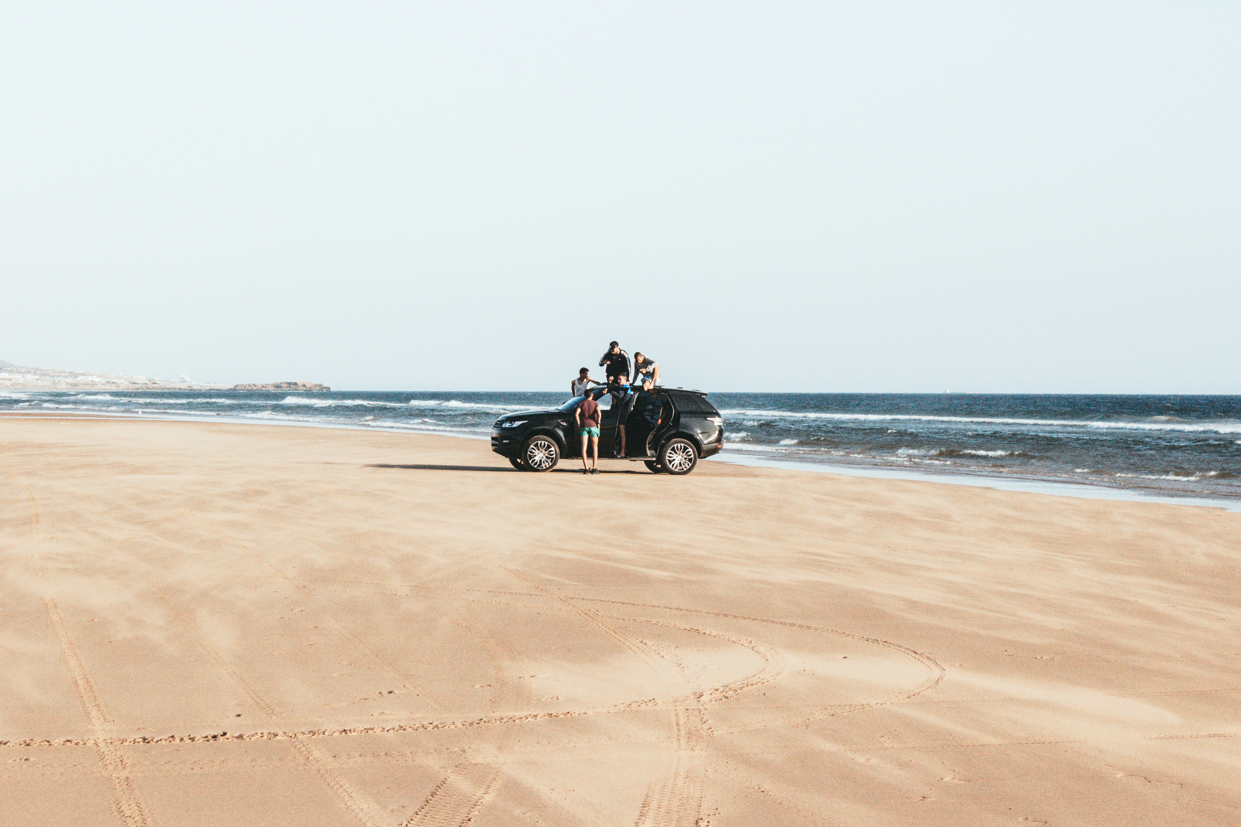 Group of friends with SUV on beach