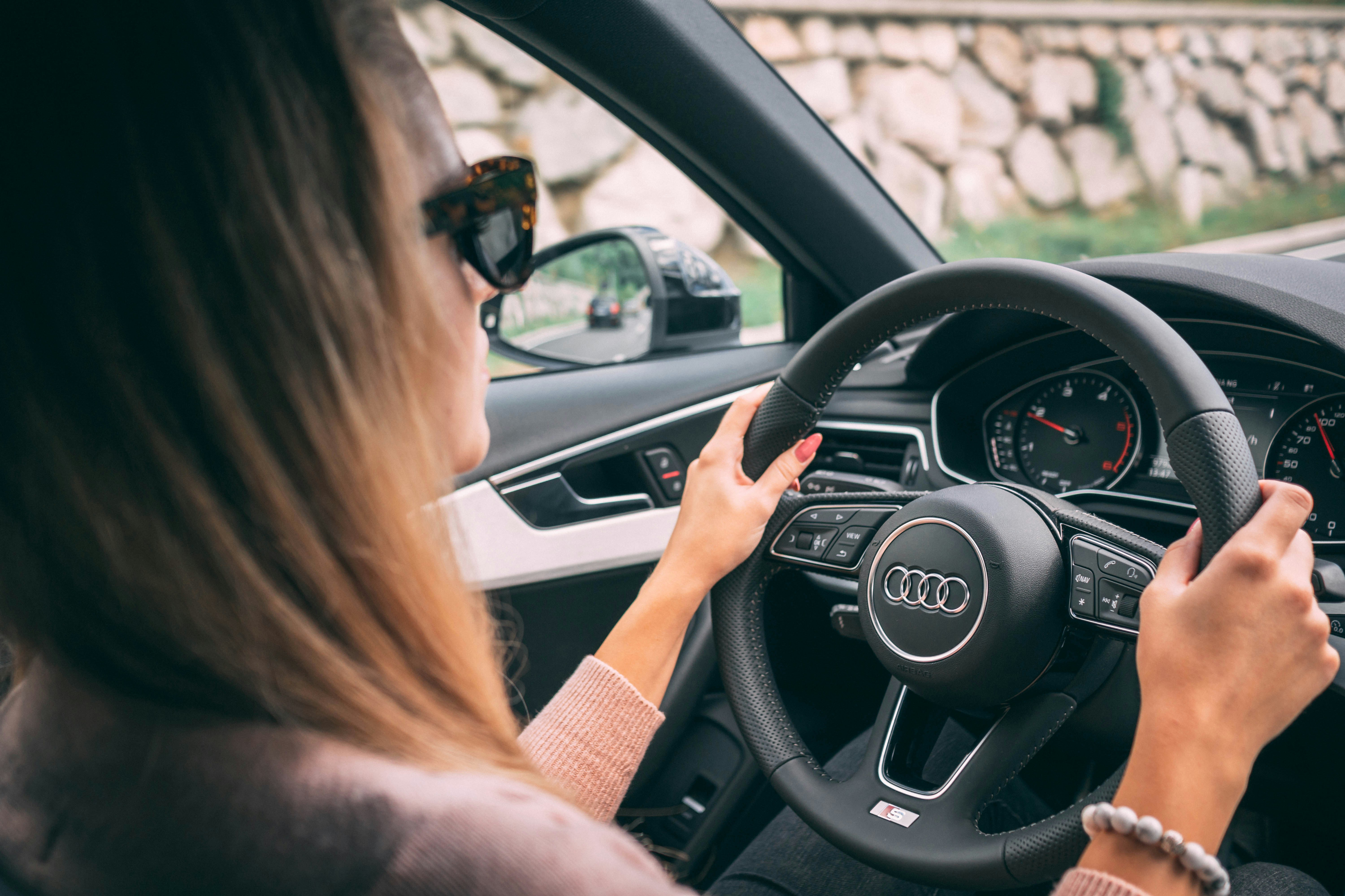 Woman driving car from interior perspective with hands on steering wheel